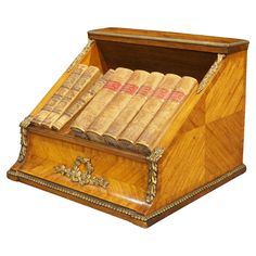 a wooden box filled with lots of books on top of a white surface and gold trimming