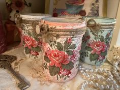 three jars with flowers painted on them sitting on a table next to pearls and beads