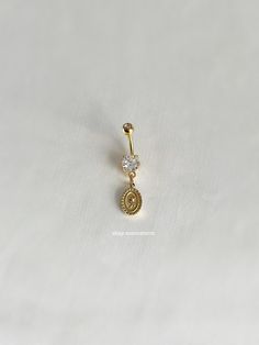 a gold charm with a diamond on the bottom and a small round pendant hanging from it's side