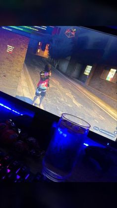 a computer screen with a video game on it and a glass of water next to it