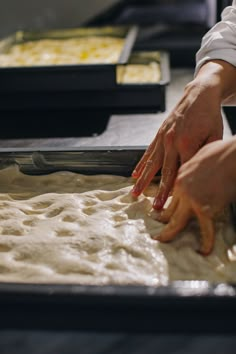 two hands reaching for dough in a pan