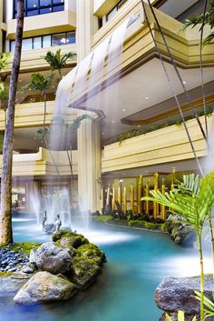 the inside of a building with water flowing from it and trees in front of it