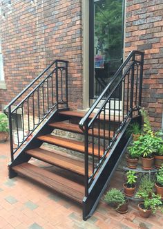 a set of stairs leading up to a brick building with potted plants on the side