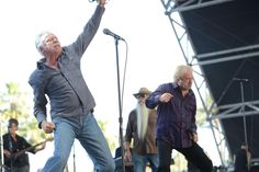 two men on stage with microphones and one man holding his arms up in the air