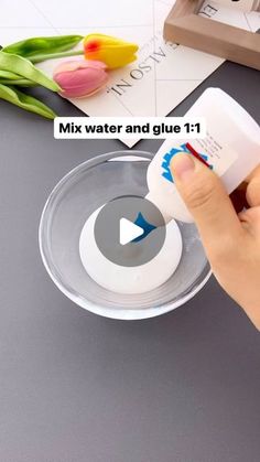 a person is pouring water into a bowl with tulips on the table next to it