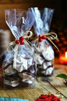 two bags filled with white chocolate sitting on top of a wooden table next to a candle