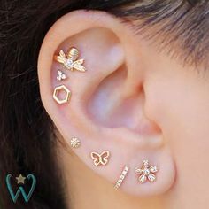 an ear with four different types of piercings on it's side and one is gold