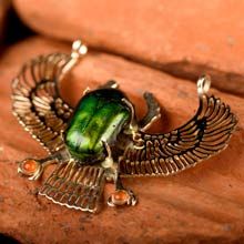 a green beetle ring sitting on top of a wooden table next to a stone wall