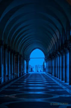 an empty hallway with columns and arches in the center at night time, illuminated by blue light