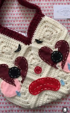 a crocheted purse with hearts and eyes on the front is sitting on a table