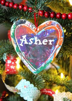 an ornament hanging from a christmas tree with the word asher painted on it