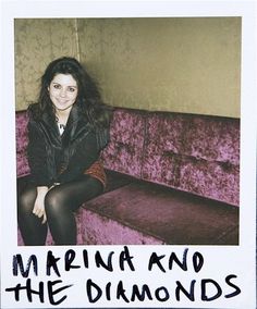 a woman sitting on top of a purple couch next to a sign that says marina and the diamonds