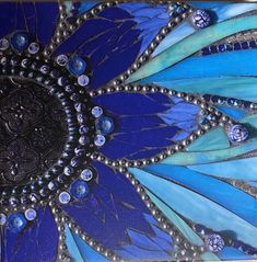 a close up view of an art work with blue feathers and beads on the surface