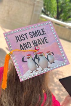 Pink graduation cap with the “just smile and wave” Penguins of Madagascar quote. Bluey Grad Cap, Graduation Hat Ideas High School, Phineas And Ferb Graduation Cap, Senior Cap Decoration Ideas, Outer Banks Graduation Cap, Matching Grad Caps For Best Friends, Cute Grad Cap Ideas High Schools, Garfield Graduation Cap, High School Graduation Cap Designs Funny