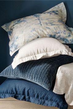 several pillows stacked on top of each other in a room with blue walls and wooden flooring