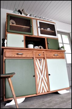 a green and white cabinet sitting in a room next to a table with a chair