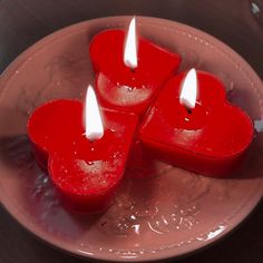 three red heart shaped candles on a plate