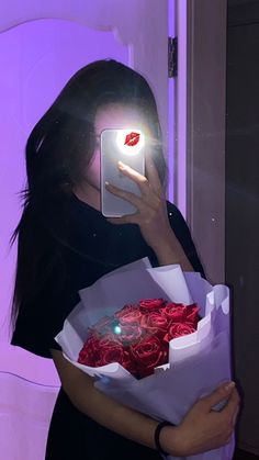 a woman taking a selfie while holding a bouquet of roses