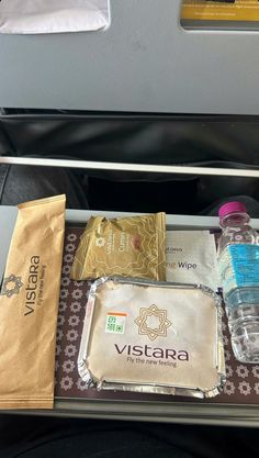 an airplane tray with water, food and other items on the trays next to it