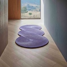 three circular rugs on the floor in front of an open window with mountains in the background