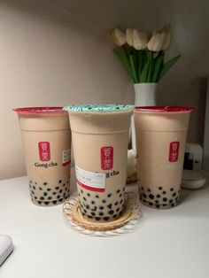 three coffee cups sitting next to each other on a table with flowers in the background