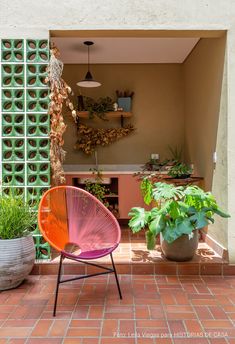 an outdoor kitchen with potted plants on the side and a colorful chair in front