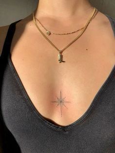 a woman's chest with a star tattoo on her chest and a cross in the middle