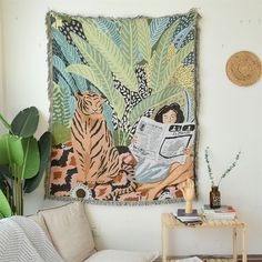 a tapestry hanging on the wall next to a table with a chair and potted plant