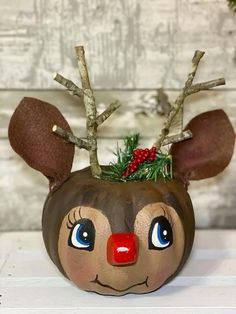 a painted pumpkin with reindeer's head and nose is shown in front of a wooden background