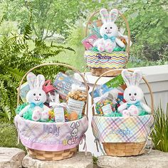 two baskets filled with stuffed animals sitting on top of a stone wall next to plants