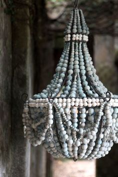 a chandelier made out of beads hanging from a ceiling in an old building