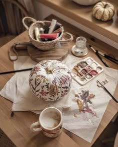 a wooden table topped with lots of crafting supplies next to a cup and saucer