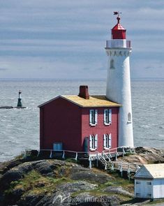 a red and white light house sitting on top of a rock next to the ocean