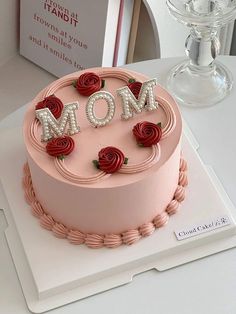 a pink cake decorated with roses and the word mom spelled out in letters on top