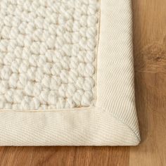 a close up view of a white rug on a wooden floor with wood grained floors