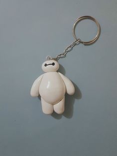 a white teddy bear shaped keychain on a gray surface