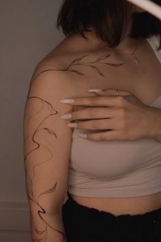 a woman with tattoos on her arm and shoulder is holding a white object in front of her face