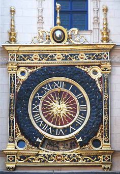 an ornate gold and black clock with roman numerals on the side of a building