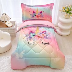 a bed with pink, blue and green comforter set on top of a white floor