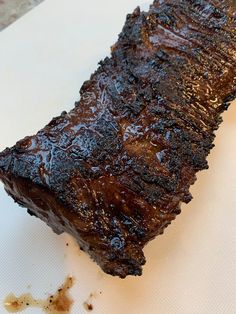 a piece of meat sitting on top of a white cutting board next to a knife