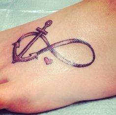 a small tattoo on the foot of a person with an anchor and ribbon around it