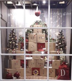 a christmas tree made out of boxes and wrapped presents in front of a store window