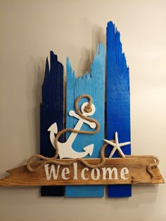 a welcome sign with an anchor and rope hanging on the wall next to blue wood planks