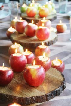 apples are arranged on wooden trays with lit candles