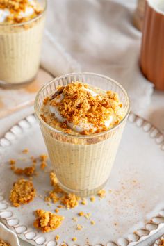 two small desserts are on a plate with some crumbs scattered around them