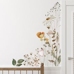 a wall with flowers painted on it and a baby crib in the foreground