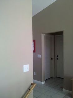 an empty room with tile flooring and white walls in the corner, looking into another room