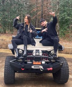 two people sitting on top of a jeep