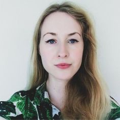 a woman with long blonde hair wearing a green and white shirt looking at the camera