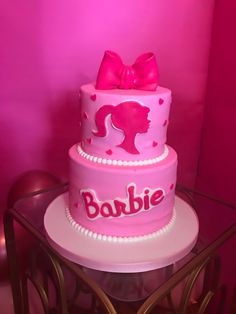 there is a pink cake that has a bow on it and the word barbie written in large letters